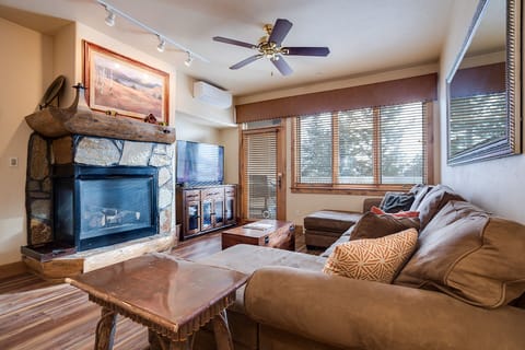Cozy up by your stone fireplace in this comfortable living room with plush seating and mountain views through large windows.