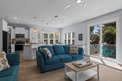 Relax in your bright, coastal living space where the modern kitchen flows seamlessly into the comfortable seating area with tropical balcony views.