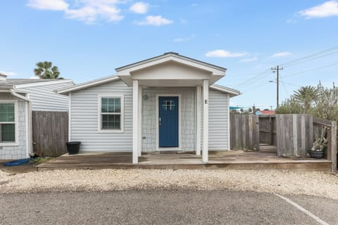 Charming coastal cottage with welcoming blue door and private covered porch, perfectly positioned for your beach getaway.