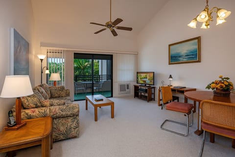 Unwind in your spacious living area with tropical decor, vaulted ceilings, and your own balcony overlooking lush greenery—perfect for relaxing after exploring the island.