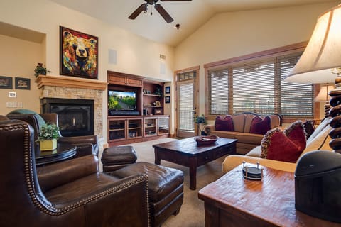 Sink into plush leather seating by your crackling fireplace, where vibrant art and warm wood create your perfect retreat.