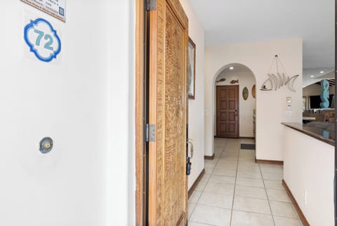 Step through the intricately carved wooden door into your serene coastal retreat, where nautical accents and gleaming tile floors welcome you home after a day of adventure.