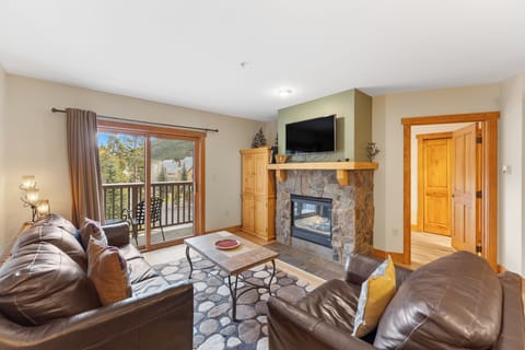 Cozy up in this warm living room where leather seating surrounds a stone fireplace, perfect for relaxing after your mountain adventures.