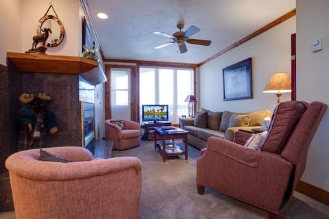 Unwind in your cozy living room with plush seating, warm fireplace, and mountain views through large windows.