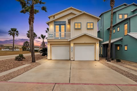 Charming coastal home with palm trees and vibrant sunset skies creating a perfect beachside retreat atmosphere.