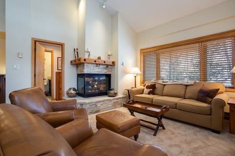 Unwind by the crackling fireplace in your cozy living room, where plush leather chairs and soft lighting create the perfect mountain retreat ambiance.