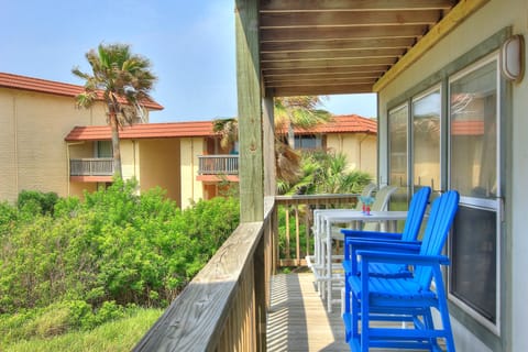 Step onto your private balcony where bright blue chairs invite you to relax with tropical views of palm trees and resort buildings.