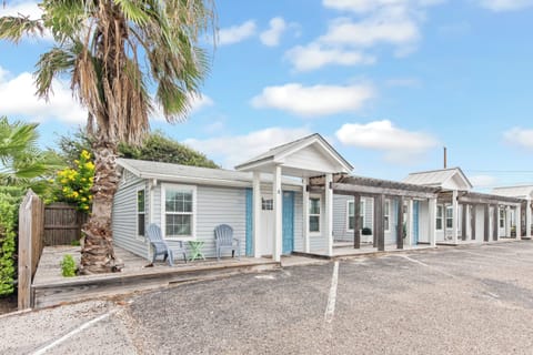 Charming coastal cottage complex with tropical palm trees and convenient parking, perfect for a relaxing beach getaway.