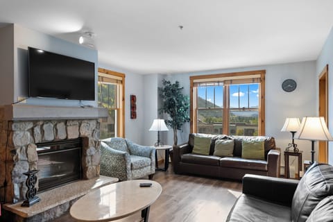 Unwind in your cozy living room with mountain views, stone fireplace, and comfortable seating perfect for evening relaxation.