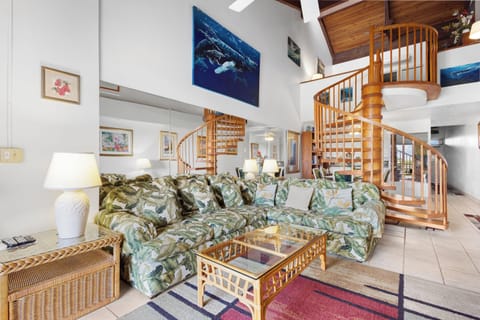 Unwind in your spacious, sunlit living room with vaulted ceilings, tropical décor, and a stunning spiral staircase inviting you to explore your vacation haven.