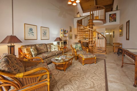 Unwind in your airy living space with its soaring wood-paneled ceiling and charming spiral staircase. Sink into the cushioned rattan seating and let the tropical decor transport you to island relaxation.