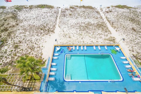 A refreshing pool area features lounge chairs and a view of the sandy beach, perfect for relaxation and fun in the sun