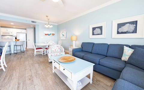 Relax in the inviting living area with a plush sofa, coastal decor, and a dining space perfect for meals and gatherings