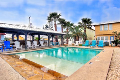 Dive into crystal-clear waters surrounded by swaying palms and colorful lounge chairs - your tropical poolside paradise awaits.