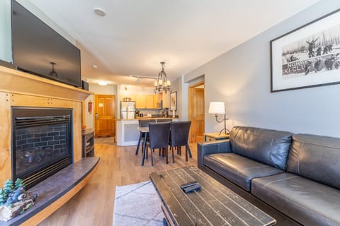 Relax in your open-concept living space with cozy fireplace, leather seating, and modern kitchen - perfect for après-ski evenings.