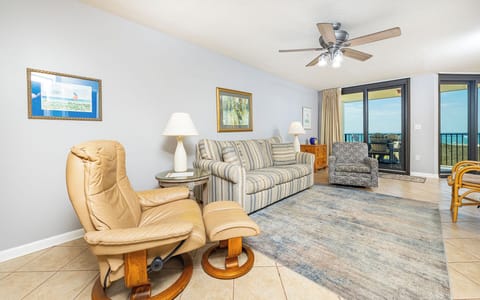 Cozy living area features a striped sofa with queen sleeper, accent chairs, and a view of the balcony