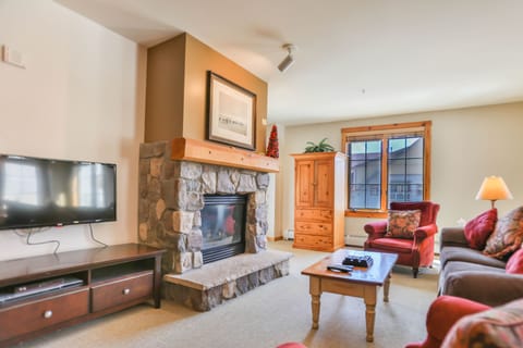 Cozy up in your warm living space with a crackling stone fireplace, leather seating, and mountain views through sunny windows.