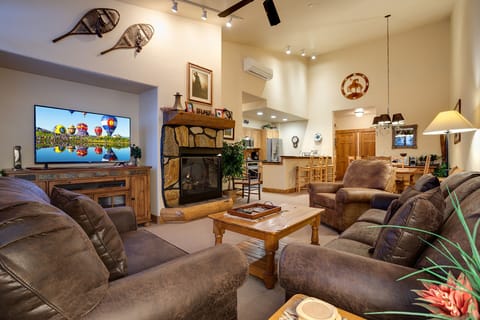 Unwind in your spacious living area with plush leather seating around the stone fireplace, perfect for cozy evenings after mountain adventures.