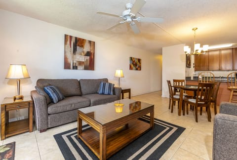 Your spacious open-concept living area flows seamlessly into the dining space, where you can unwind on the comfortable sofa or enjoy meals together at the wooden table under warm lighting.