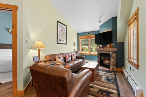 Sink into plush leather sofas by the flickering stone fireplace, your cozy mountain retreat warmed by natural wood accents and inviting you to stay a while.
