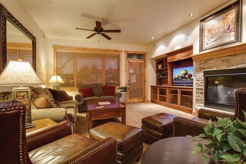 Sink into plush leather seating by your stone fireplace, where rich wood tones and warm lighting create the perfect evening retreat.