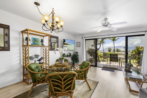 Relax in your tropical-themed living space, where natural light floods through sliding doors opening to lush palm views and your private patio seating area.