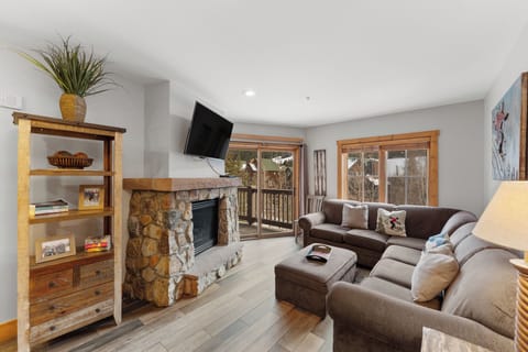 Sink into your cozy sectional by the stone fireplace, where mountain views and warm wood accents create your perfect alpine retreat.