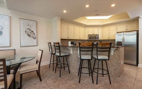 The kitchen features granite countertops, stainless appliances, and a cozy dining area with a glass table for shared meals