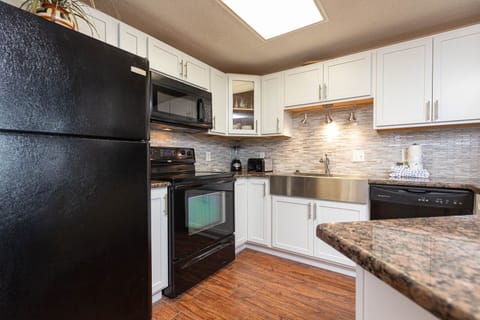 Cook and gather in this kitchen featuring sleek black appliances and stylish granite countertops and backsplash