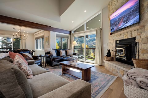 Unwind in your cozy living room featuring a stone fireplace, mountain views, and plush seating perfect for relaxing evenings.