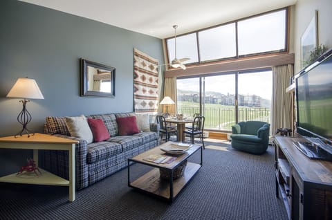 Relax in your thoughtfully designed living space with cozy plaid seating, panoramic windows, and a perfect dining nook for morning coffee.