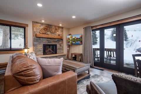 Cozy up by your stone fireplace while watching snowy slopes through panoramic windows in this ski-in retreat.