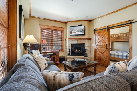 Cozy up by the stone fireplace while the kids enjoy bunk beds behind rustic sliding doors.