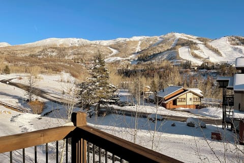 Breathtaking winter mountain panorama with pristine ski slopes, snow-covered peaks, and charming alpine village nestled below under brilliant blue skies.