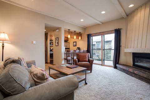 Unwind in your spacious living room featuring plush seating, warm fireplace, and an open layout connecting to your fully equipped kitchen.