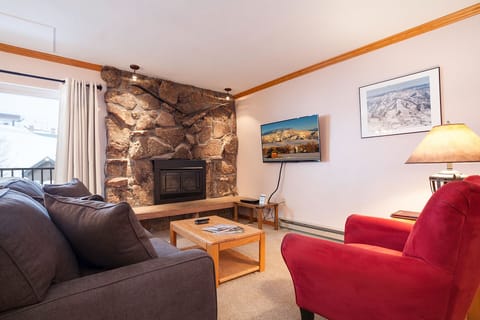 Cozy up by the stone fireplace in this mountain retreat living room with plush seating and warm lighting.