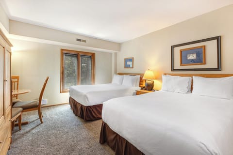 One of the bedrooms offer two queen beds with wooden furniture.