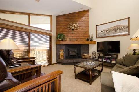 Unwind in your inviting living space featuring rich wood accents, a cozy fireplace, and modern entertainment center for perfect mountain evenings.
