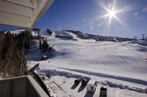 Bright winter sun illuminates pristine ski slopes and mountain peaks visible from the property balcony, creating perfect conditions for alpine adventures.
