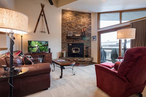 Cozy up by your stone fireplace in this inviting living space with plush seating and mountain views from your private balcony.