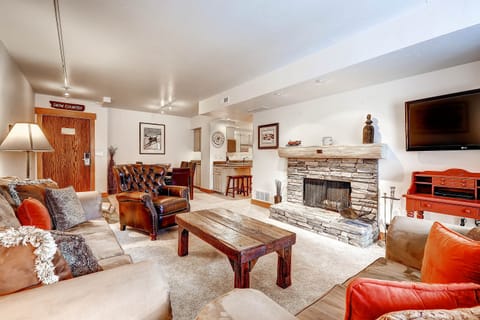 Park Station 134's living room with greige upholstered couch and loveseat, leather club chair, and fireplace.