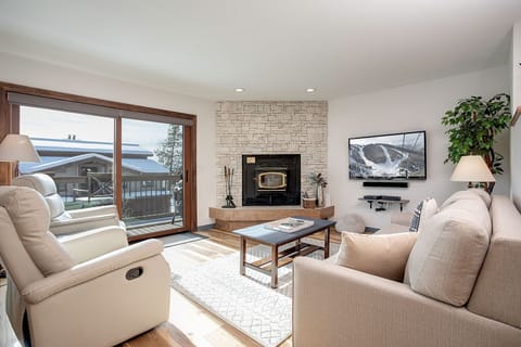 Unwind in your cozy living room with plush seating, a warm fireplace, and stunning mountain views through large windows.