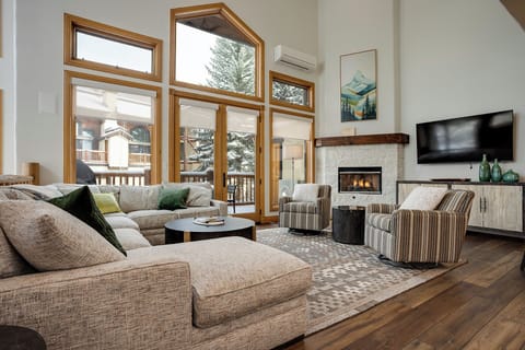 Sink into plush sofas by the crackling fireplace, where soaring windows frame snowy mountain views and cozy evenings await.