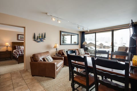 Relax in your cozy living room with comfortable leather seating and warm lighting while enjoying mountain views through large windows.