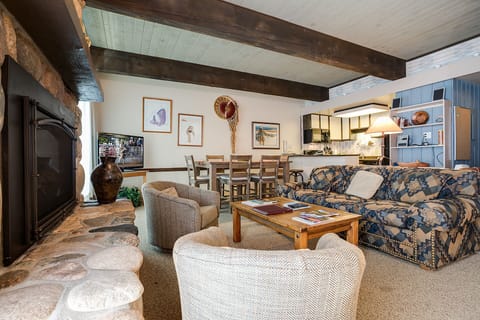Relax by the fireplace in your open living space with rustic beams and modern kitchen nearby.
