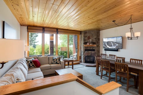 Cozy mountain retreat with stone fireplace, plush seating, and panoramic windows framing alpine views for your perfect getaway.