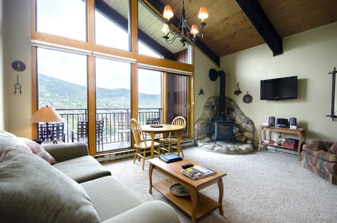 Relax in your spacious living area with soaring ceilings, cozy fireplace, and stunning mountain views through floor-to-ceiling windows.