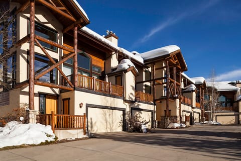Modern mountain townhomes featuring rustic timber accents and snow-dusted roofs under brilliant blue winter skies.