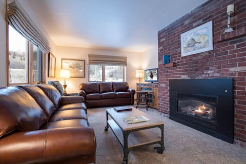 Sink into plush leather sofas by your crackling fireplace, where brick walls and mountain views create the perfect alpine retreat.