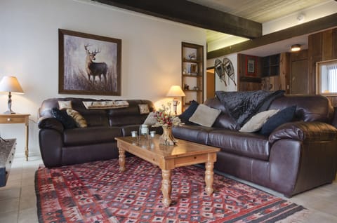 Sink into plush leather sofas in your cozy living room, where rustic wood beams and mountain artwork create a warm retreat after your day's adventures.